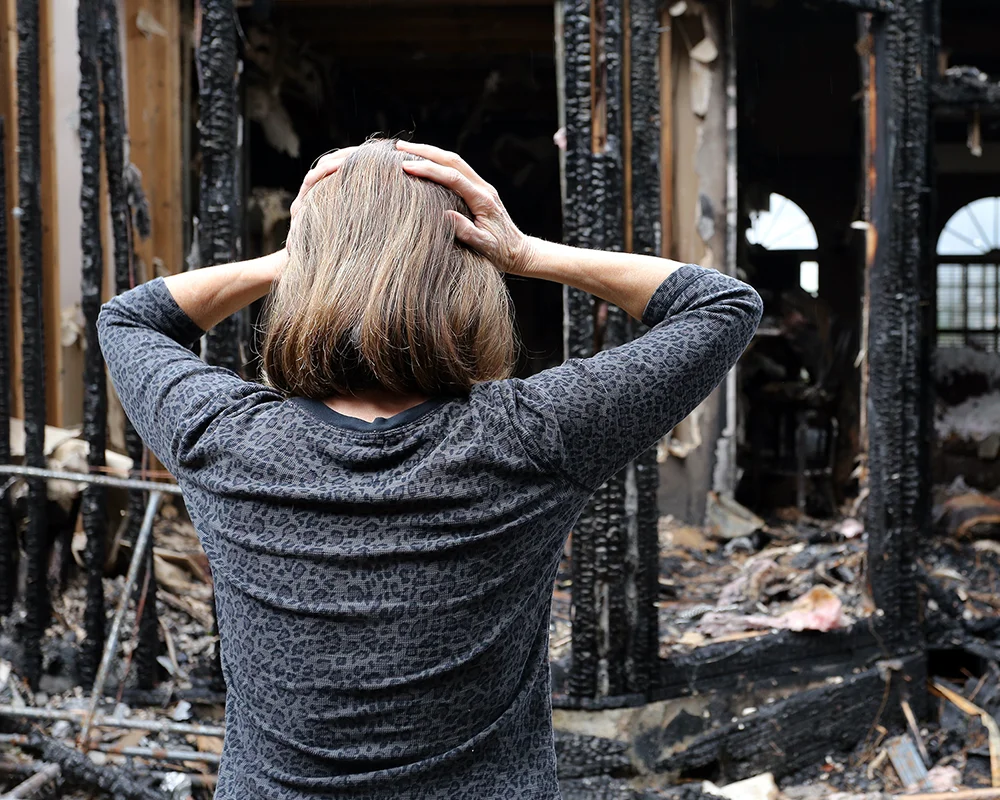 Femme devant sa maison ruinée par le feu
